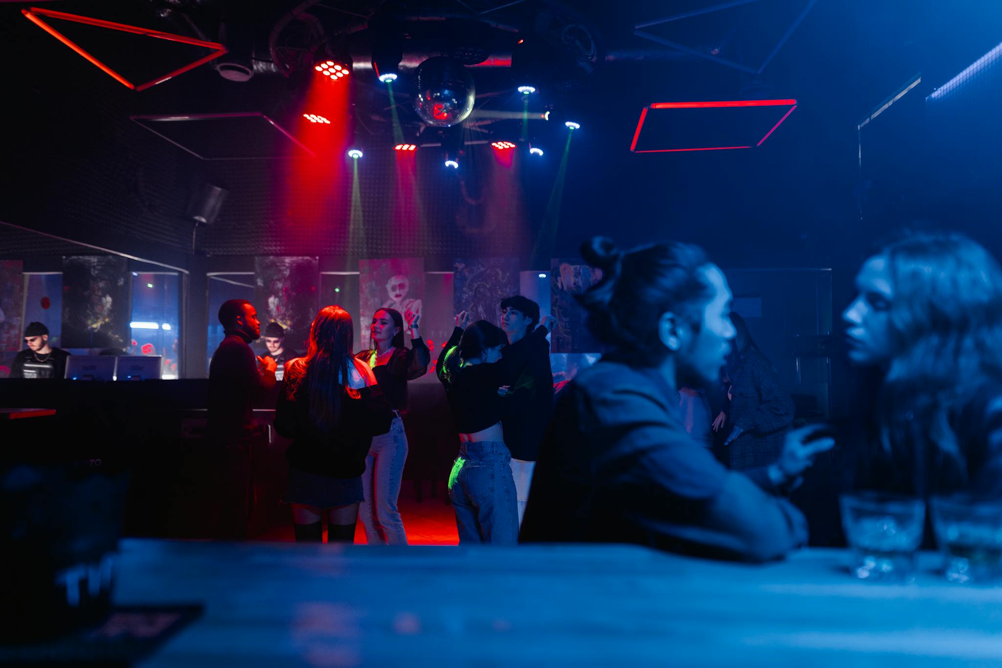 Vibrant nightclub scene featuring people dancing and socializing under colorful lights.